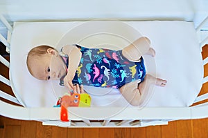 Baby girl lying in co-sleeper attached to parents` bed