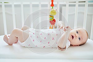 Baby girl lying in co-sleeper attached to parents` bed