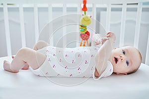 Baby girl lying in co-sleeper attached to parents ` bed