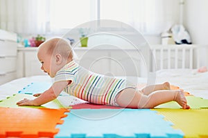 Baby girl lying on colorful play mat on the floor