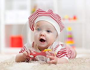 Baby girl lying on the floor and plays with toy indoor