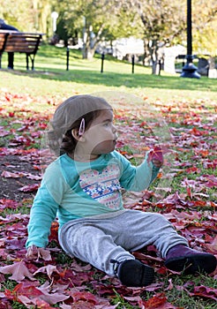 Baby Girl lying on red leaves at Autumn