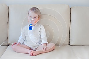 Baby girl making inhalation with mask on her face photo