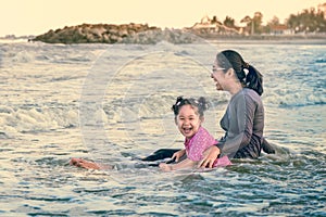 Baby girl and mother playing in the sea