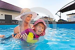 Baby girl with mother in swimming pool learn to swim.