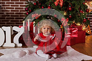 Baby girl near luxury red christmas tree