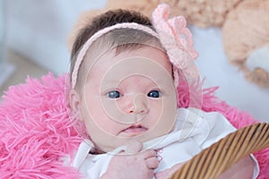 Baby girl newborn portrait in pink blanket lying in basket, cute face, new life