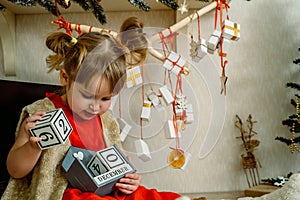 Baby girl opening Christmas presents. candy and gifts in advent calendar on winter morning