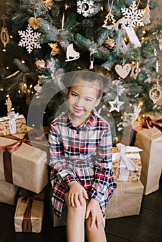 Baby girl in p dress sitting near Christmas tree in gifts