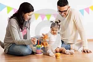 Baby girl with parents playing with toy rabbit