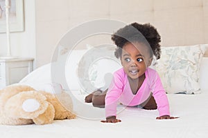 Baby girl in pink babygro crawling on bed photo