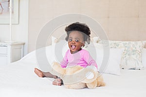 Baby girl in pink babygro sitting on bed photo