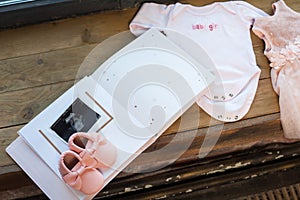 Baby girl pink dress clothes with newborn book album, body and little shoes and ultrasound scanning fetal photo