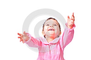 Baby girl in pink dress sitting with hands up