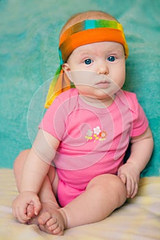 Baby girl in a pink t-shirt with scarf on a green background