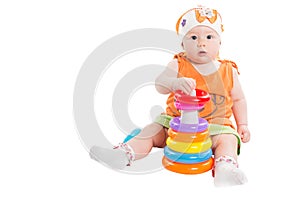 Baby girl playing with colored pyramid build from rings isolated on white background