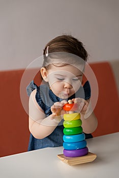 Baby girl playing colourful toy wooden pyramid.