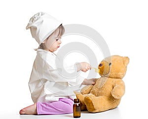 Baby girl playing doctor and giving remedy to toy photo