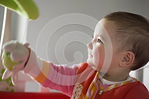 Baby girl playing with her baby musical mobile toy