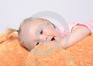 Baby girl playing with a huge teddy bear.