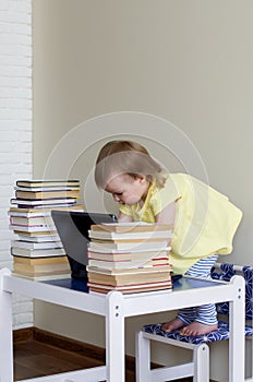 Baby girl playing with laptop toy between books