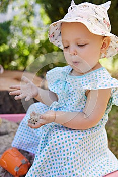 baby girl playing in sand on outdoor playground