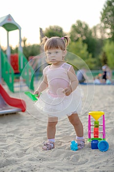 Baby girl playing in sandbox in kindergarten.ittle girl plays with toys in the sand.