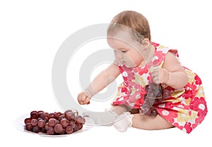 Baby girl plays with grapes