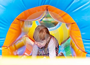 A baby girl plays in an inflatable attraction in an amusement park. Cute child on the playground. An Active Child Having Fun In A