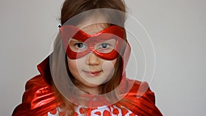 Baby girl plays superhero. Funny child in a red raincoat and mask playing power super hero. Superhero and power concept