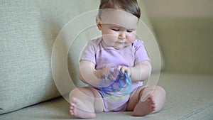 Baby girl plays with the toy sitting on the couch