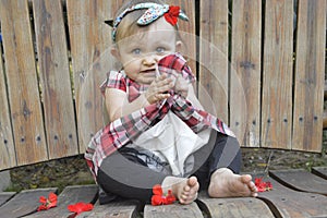 Baby Girl posing adorable on wood swing holding flowers