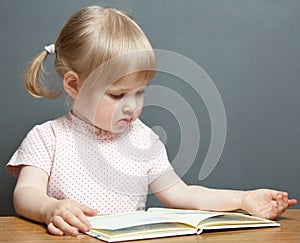 The baby girl is reading the book
