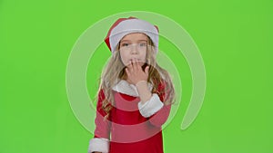 Baby girl in red Christmas caps send air kisses. Green screen. Slow motion