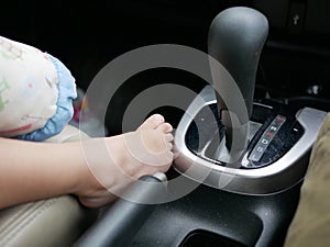 Baby girl`s feet placing next to a gear of a driving car