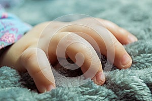 Baby girl`s hand close up. Toddler`s tiny fingers in the carpet.