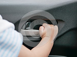 Baby girl`s hand about to pull the door handle from inside of a moving car