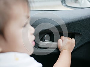 Baby girl`s hand about to pull the door handle from inside of a moving car