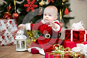 Baby girl Santa Claus in front of Christmas tree