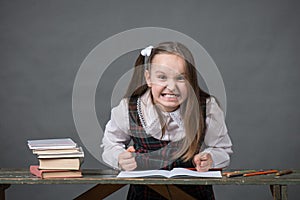 Baby girl in a school uniform sitting at a table with books