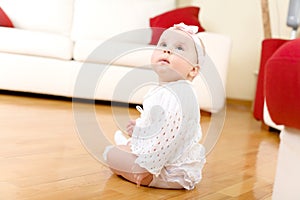 Baby girl seated on a hardwood floor