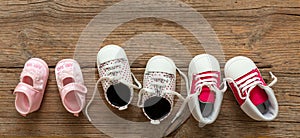 Baby girl shoes variety on wooden background, top view