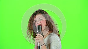 Baby girl sings in retro microphone fiery songs. Green screen