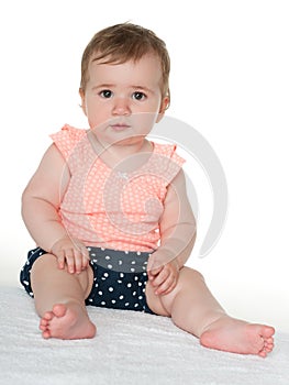 Baby girl sits on the white towel