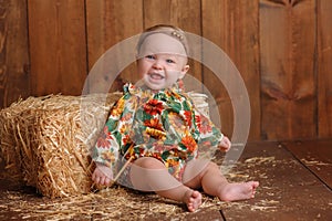 Baby Girl Sitting Against a Straw Bale