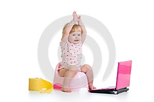 Baby girl sitting on chamberpot with notebook