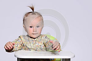 Baby girl sitting on a high chair ready to eat.