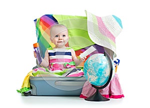 Baby girl sitting in suitcase with things for