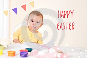 Baby girl sitting at the table and painting holiday easter eggs smiling happy childhood concept