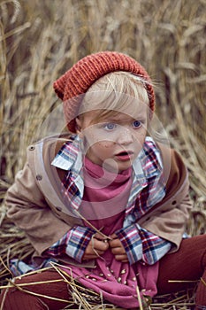 Baby girl sitting in a warm orange hat